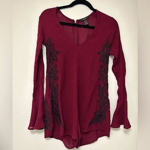 Long sleeve maroon romper with flared sleeves. Black embroidered details.